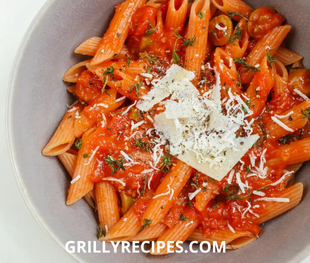 A bowl of creamy chicken pasta garnished with fresh herbs and parmesan cheese.